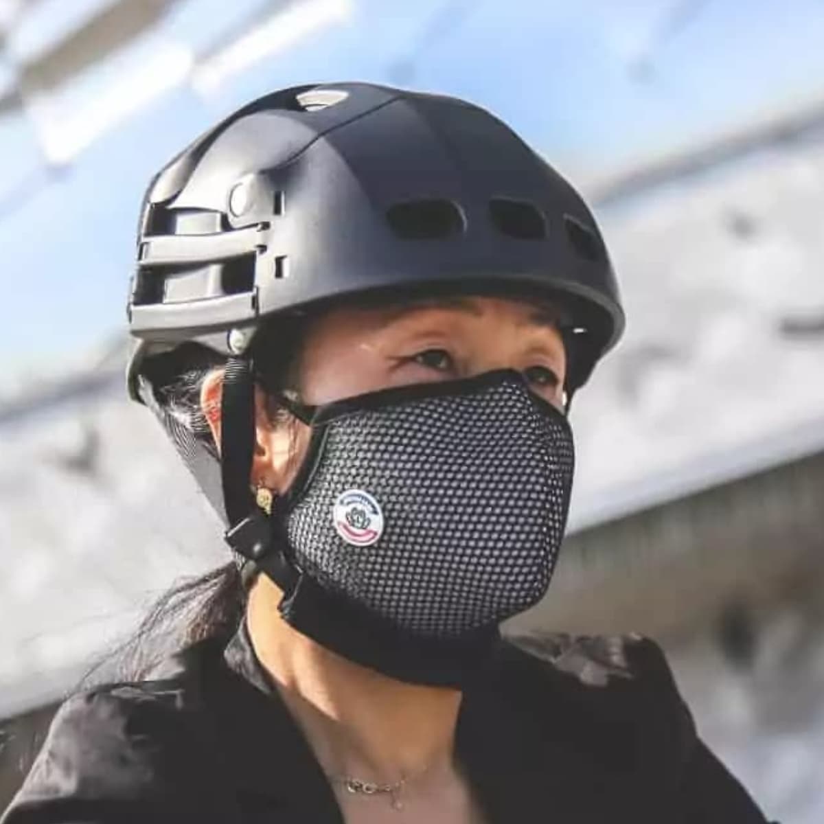 Femme cycliste casquée portant un masque vélo Frogmask noir et blanc