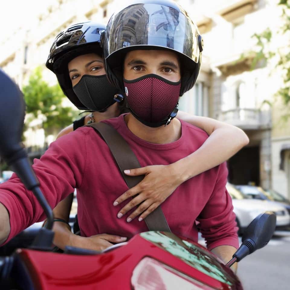 Couple sur un scooter portant des masques antipollution Frogmask bordeaux et noir