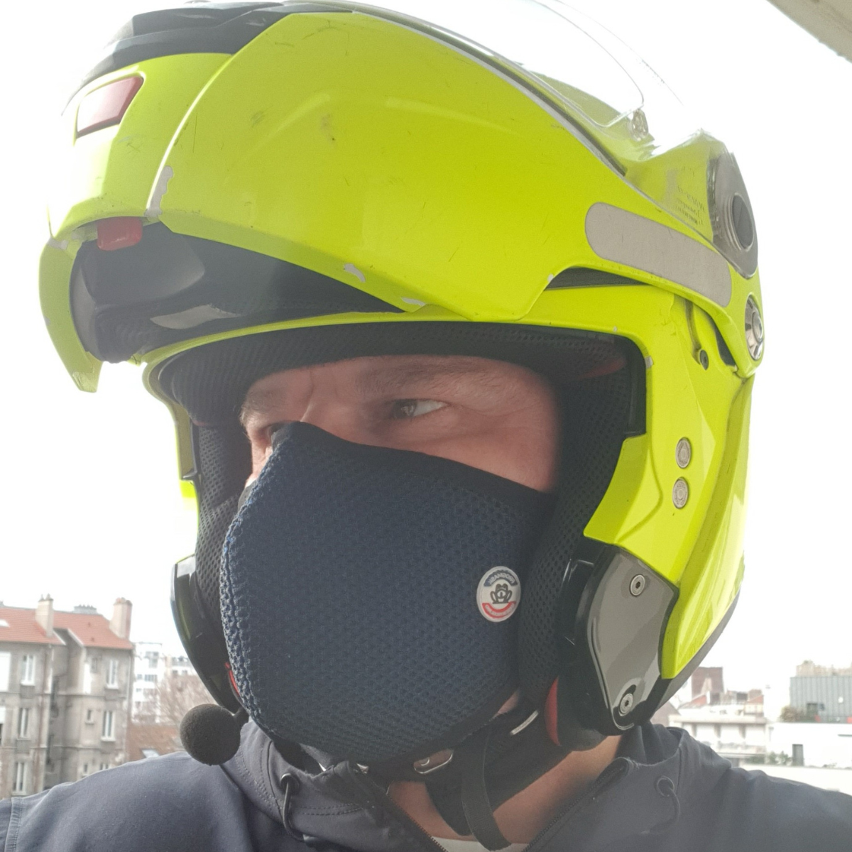 Motard casqué avec un masque pollution Frogmask bleu