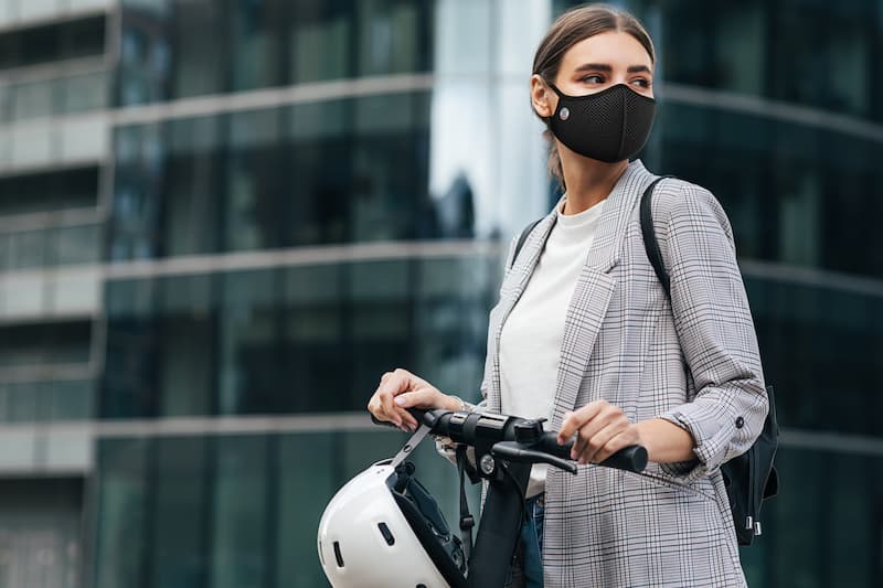 Jeune femme sur une trottinette portant un masque antipollution Frogmask noir